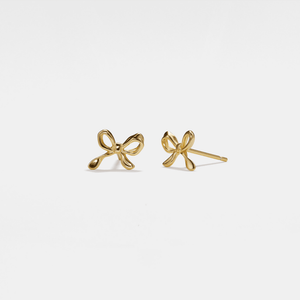 Gold bow-shaped earrings on a light gray background