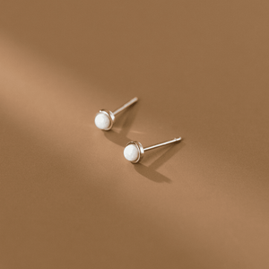 Pair of pearl stud earrings on a brown background