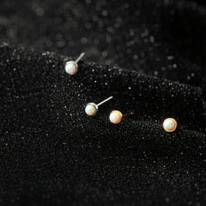 Set of pearl stud earrings on a black textured background