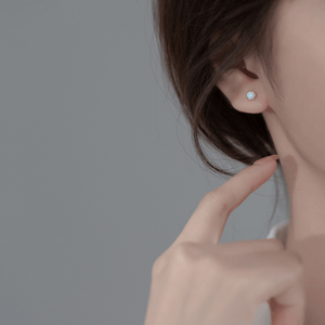 Close-up of a person wearing a blue gemstone earring with a neutral background