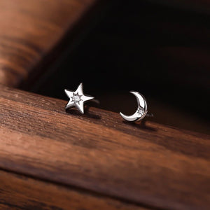 Silver star and moon earrings on a wooden surface