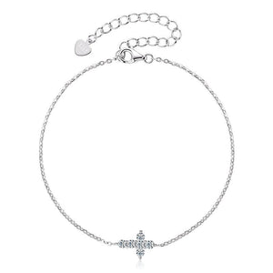 A sterling silver bracelet with a small cross charm adorned with moissanite stones, displayed against a white background.