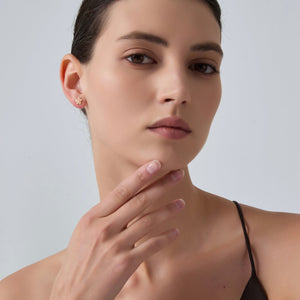 Woman wearing gold earrings with a plain background