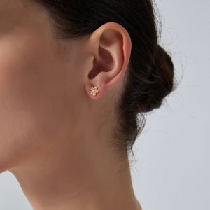 Close-up of an ear wearing a gold earring with a plain background