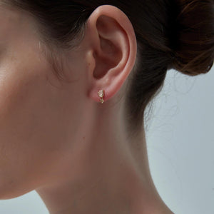 Close-up of a person wearing a gold earring with a clear background