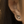 Close-up of an ear wearing a silver earring with a flame design.