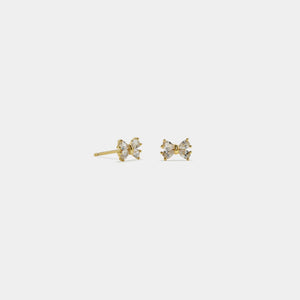 Gold bow-shaped earrings on a light gray background