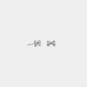 Pair of silver bow-shaped earrings on a light gray background