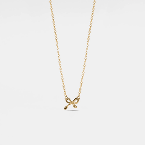 Gold necklace with a bow pendant on a light gray background