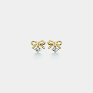 Gold bow-shaped earrings with embedded diamonds on a light gray background