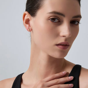 Close-up of a woman wearing gold earrings against a neutral background