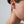 Close-up of a person wearing a gold earring on a plain background