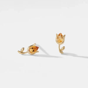 Gold earrings with citrine stones on a light gray background