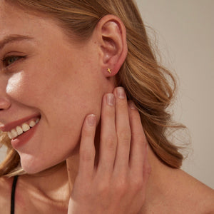 Woman wearing a gold star-shaped earring with a neutral background