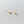 Tiny small cuboid rectangle stud earrings with gold plating on a textured beige background