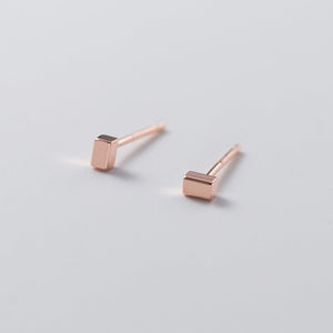 Rose gold geometric stud earrings on a light gray background