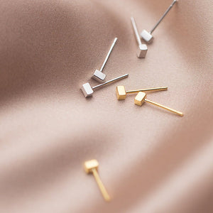 Gold and silver earrings on a soft pink fabric background