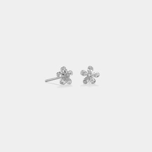 Silver flower-shaped stud earrings on a light gray background