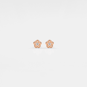 Rose gold flower-shaped earrings with clear gemstones on a light gray background