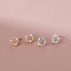 Pair of gold and silver circular earrings on a pink background