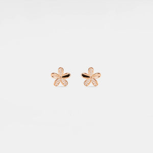 Rose gold butterfly earrings on a light beige background