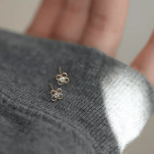 Gold flower-shaped earrings on a gray textured surface