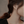 Close-up of a person wearing a gold cross earring with a blurred background