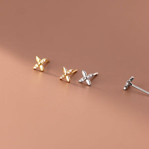 Four pairs of butterfly-shaped earrings in gold and silver on a brown background