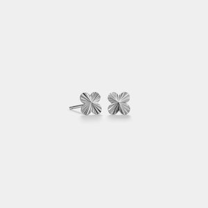 Pair of silver floral stud earrings on a light gray background