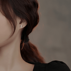 Close-up of a person wearing a small earring with a blurred background