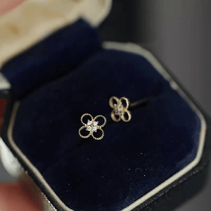 Gold flower-shaped earrings in a blue jewelry box