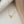 Two heart-shaped pendant necklaces, one with a gold plating and the other in silver, displayed against a grey background.