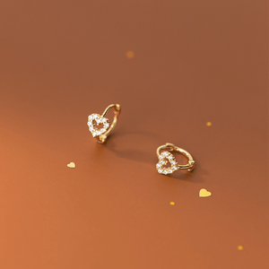 Heart-shaped gold earrings on a brown background