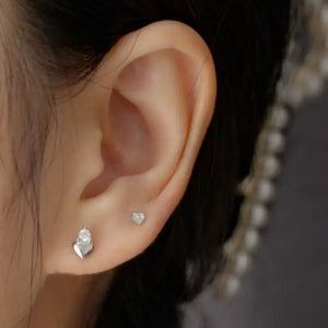 Close-up of an ear wearing two heart-shaped earrings with a blurred background