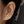 Close-up of an ear wearing gold heart-shaped earrings with a blurred background