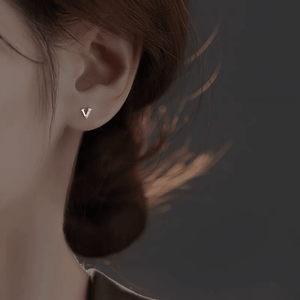 Earring with a 'V' design worn by a person against a dark background