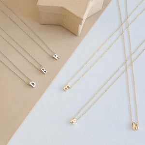 Gold and silver necklaces with letter pendants on a light gray background