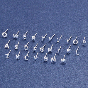 Silver letter earrings on a blue background