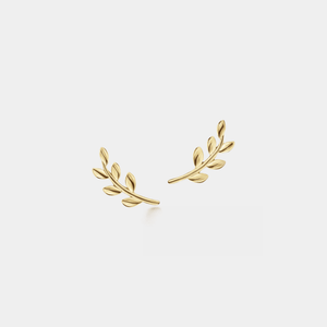 Gold leaf-shaped earrings on a light beige background
