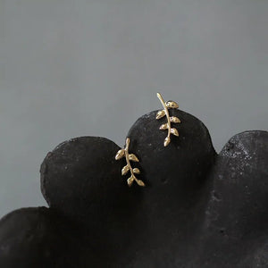 A pair of small leaf climber stud earrings made of gold-plated 925 sterling silver, displayed on a white surface.