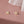 A set of two lotus flower stud earrings, one plated in silver and the other in gold, displayed against a pink background.