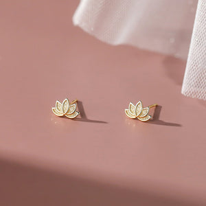 A set of two lotus flower stud earrings, one plated in silver and the other in gold, displayed against a pink background.