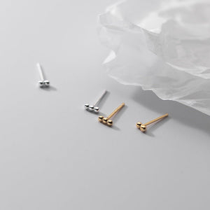 Three pairs of gold and silver stud earrings on a light gray background