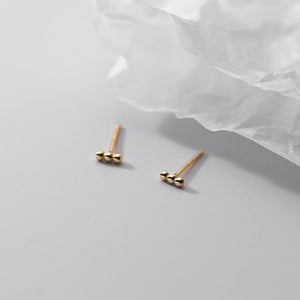 Pair of gold earrings on a light gray surface with white tissue paper