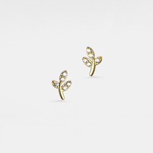 Gold earrings with leaf design on a light gray background