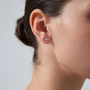Close-up of an ear wearing a colorful earring against a neutral background