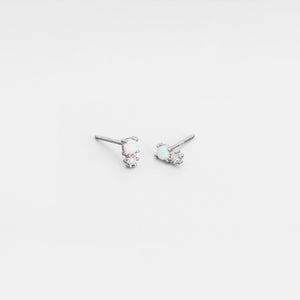 Pair of silver earrings with gemstones on a light gray background