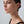 Close-up of a woman wearing pearl earrings against a neutral background