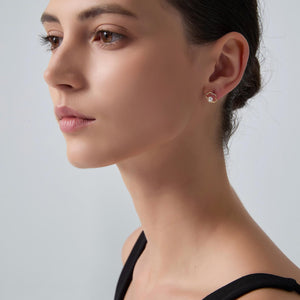 Close-up of a woman wearing pearl earrings against a neutral background
