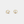 Gold earrings with pearl centers on a light gray background